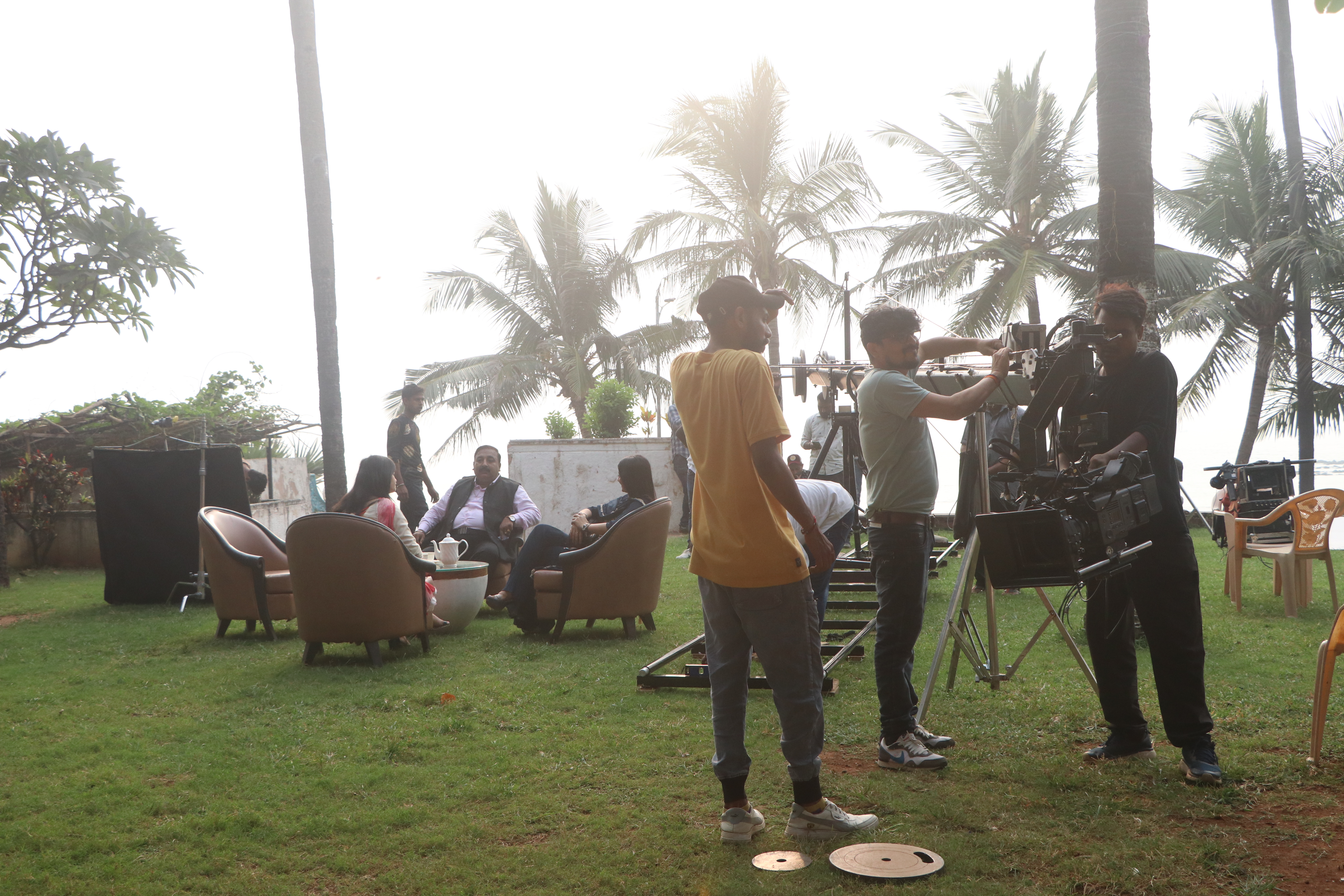 Camera crew filming actors on an outdoor set with dolly track